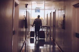Viajante caminhando com malas em corredor de hospital, ilustrando caso de seguro viagem e doença preexistente